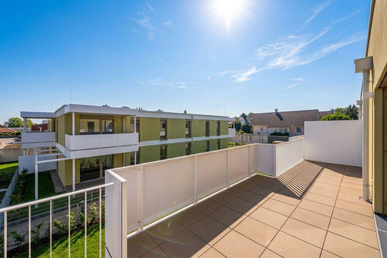 Geräumige, geflieste Terrasse mit Blick auf die umliegende Wohnbebauung und viel Sonnenlicht.