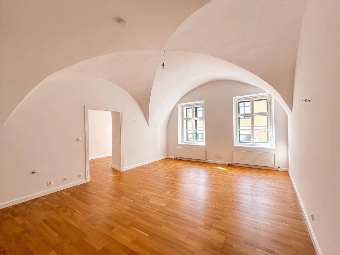 Geräumiger, leerer Raum mit beeindruckender Gewölbedecke und hellem Holzboden, bereit zur individuellen Gestaltung.