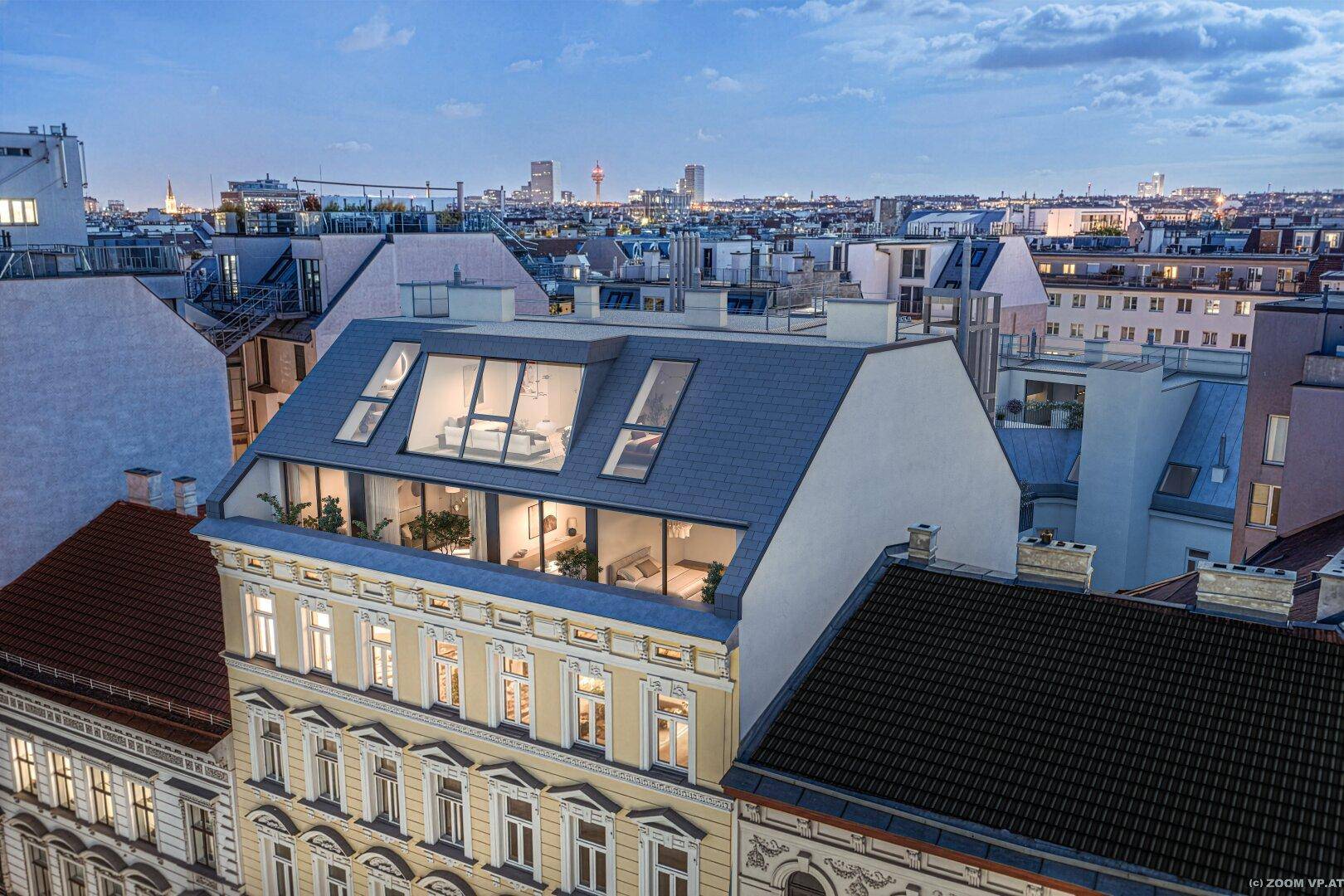 Abendliche Ansicht des Gebäudes mit modernem Dachausbau und Blick auf die Stadtkulisse.