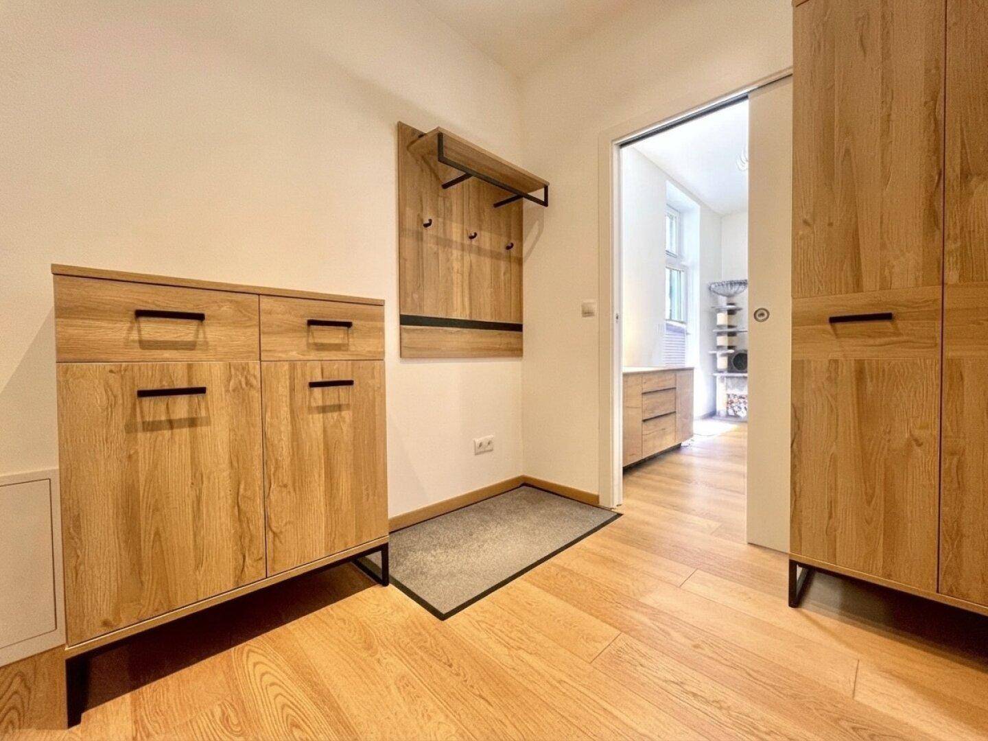 Eingangsbereich mit Holzdielenboden, Garderobe und praktischen Holzschränken.