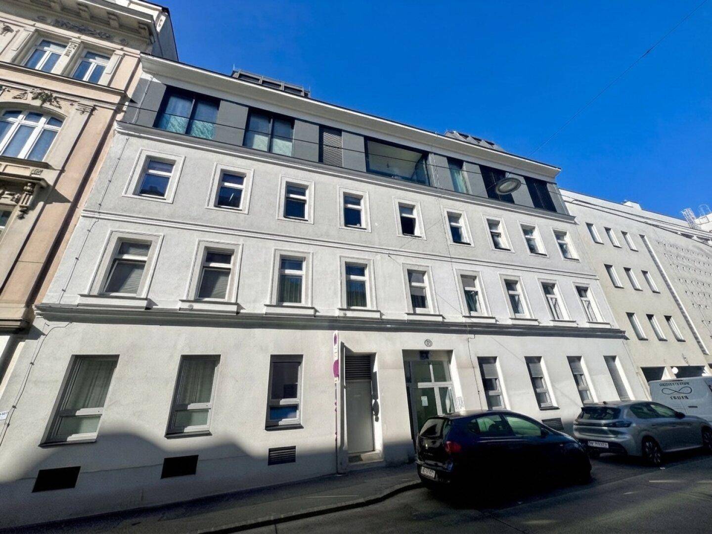 Fassade eines modernen Wohngebäudes mit mehreren Etagen und großen Fenstern.