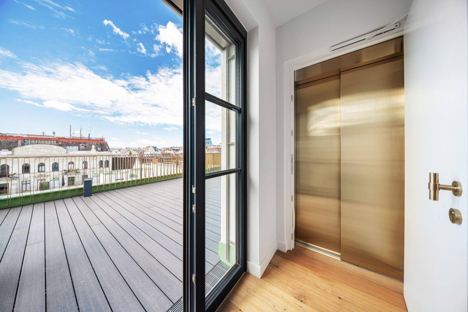 Heller Eingangsbereich mit Holzboden und modernem Aufzug, der zur Dachterrasse führt.