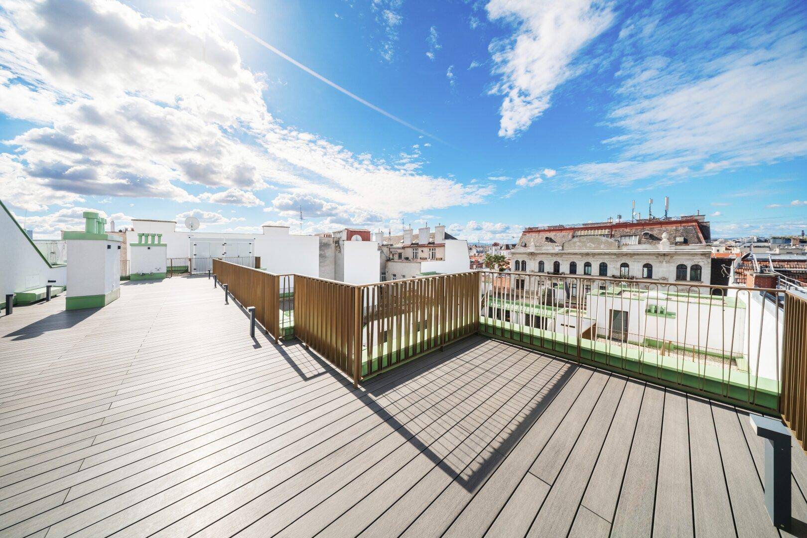 Weitläufige Dachterrasse mit Holzboden und Panoramablick über die historische Stadtkulisse.