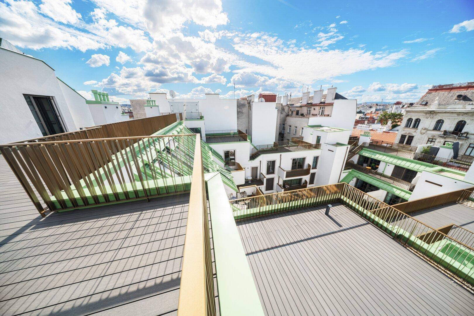 Mehrstufige Dachterrasse mit Holzboden und weitem Blick über die umliegenden Gebäude.