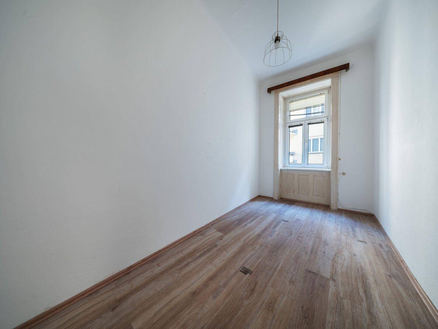 Gemütliches Zimmer mit Laminatboden und einem Fenster, das für ausreichend Helligkeit sorgt.