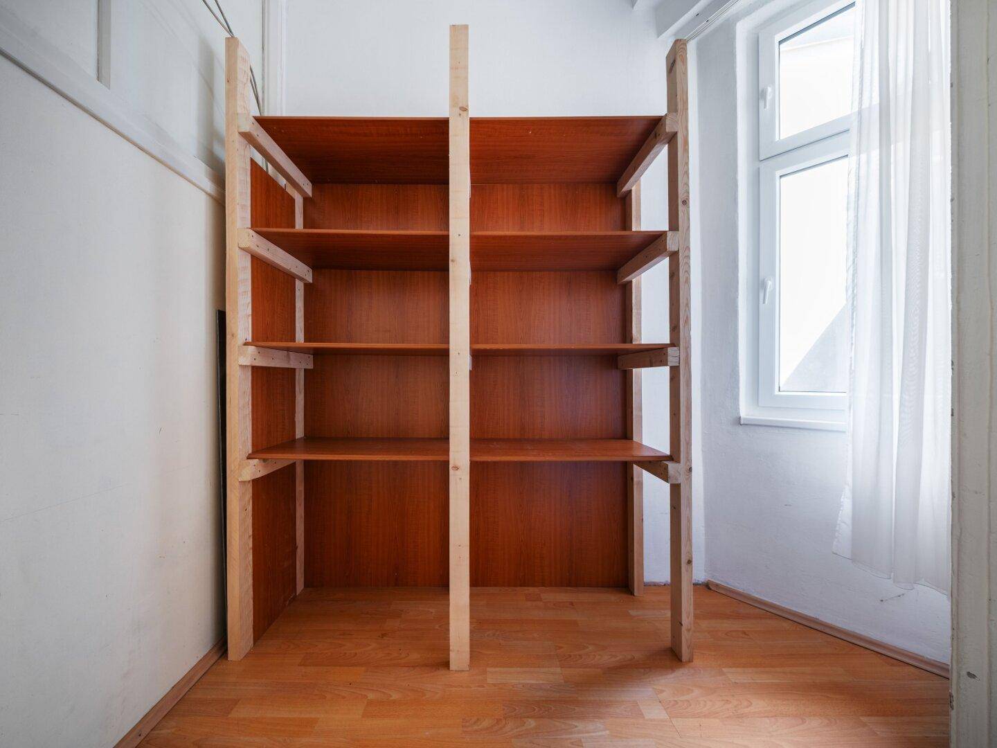 Praktischer Abstellraum mit Holzregalen und Fenster, bietet viel Stauraum.