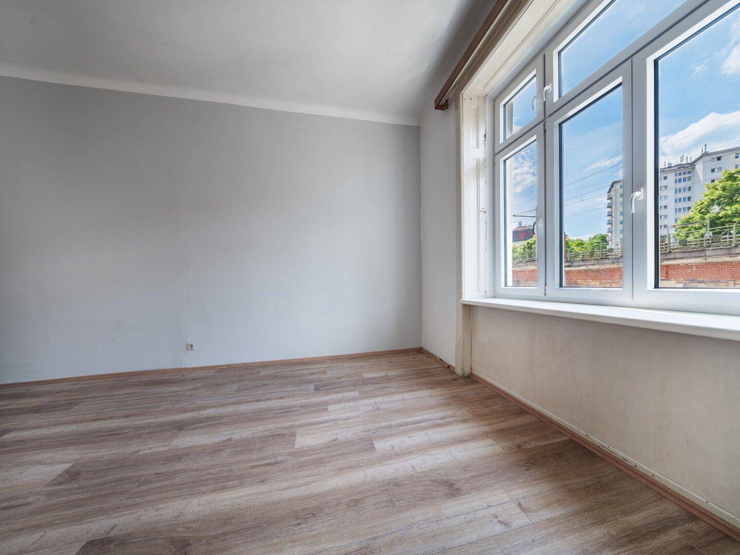 Geräumiges Zimmer mit Laminatboden und hellgrauen Wänden, ideal für ein Schlafzimmer.