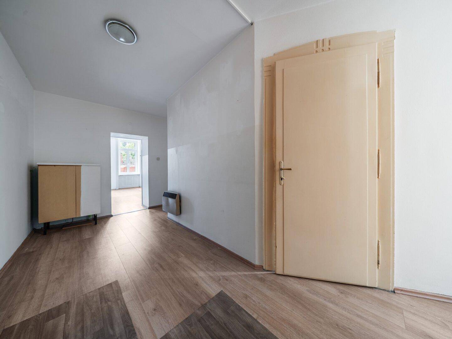 Heller Flur mit Laminatboden und einer Tür, die zu weiteren Räumen führt.
