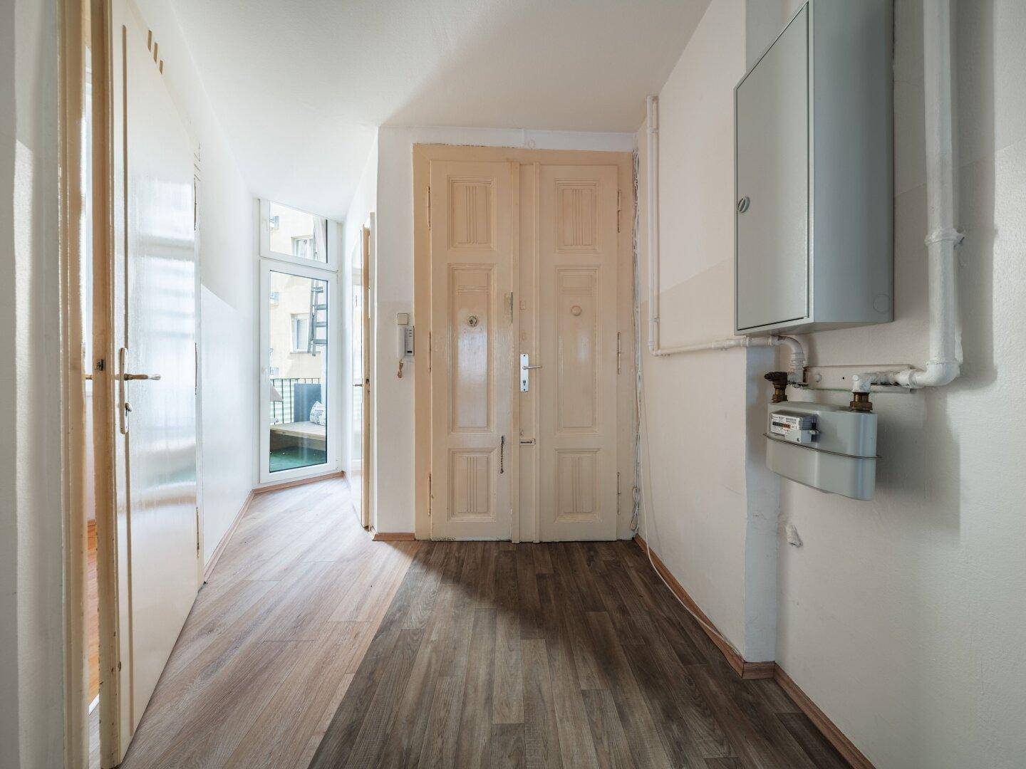 Geräumiger Flur mit Laminatboden und Zugang zu einem Balkon, ausgestattet mit einem Gaszähler.