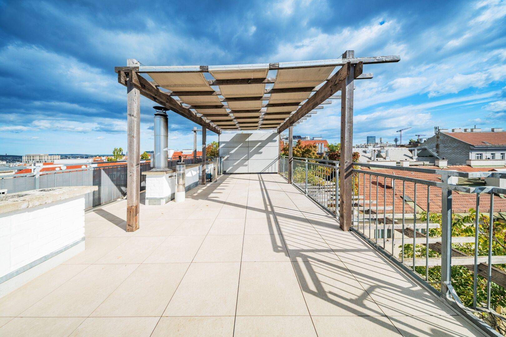 Weitläufige Dachterrasse mit Pergola und Panoramablick über die Stadt.