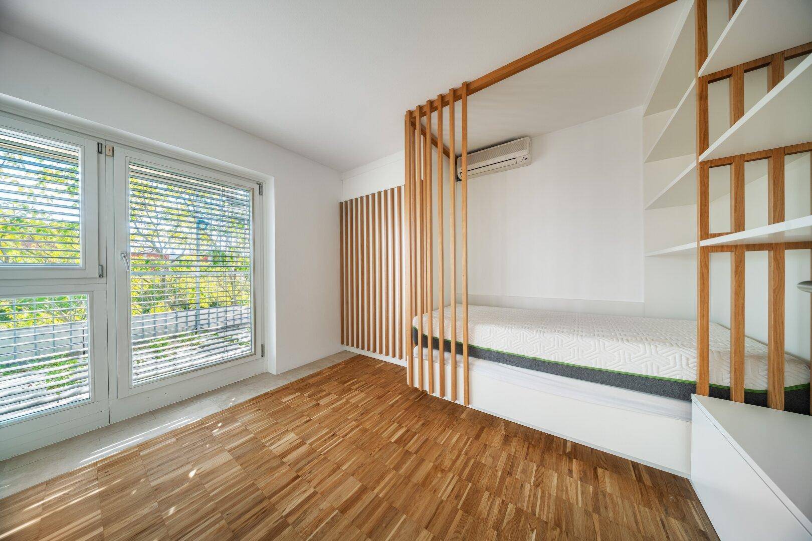 Modernes Schlafzimmer mit Parkettboden, großen Fenstern und Klimaanlage.