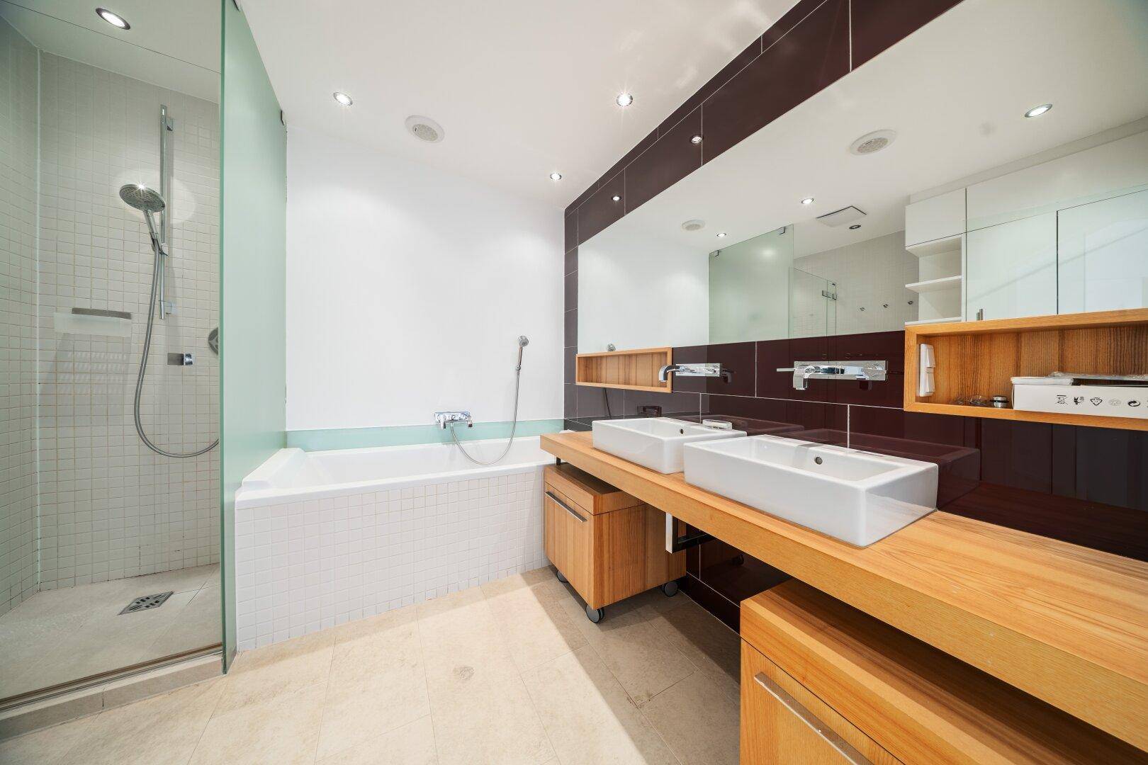 Modernes Badezimmer mit Dusche, Badewanne, Doppelwaschbecken und Holzdetails.