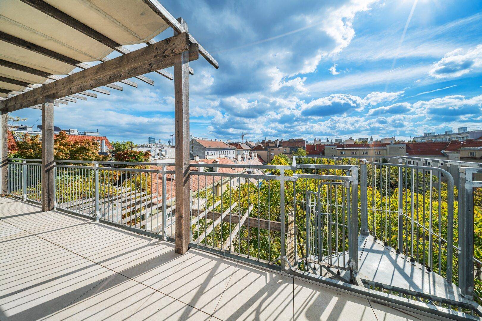 Sonniger Bereich der Dachterrasse mit Pergola und weitem Blick über die Stadt.