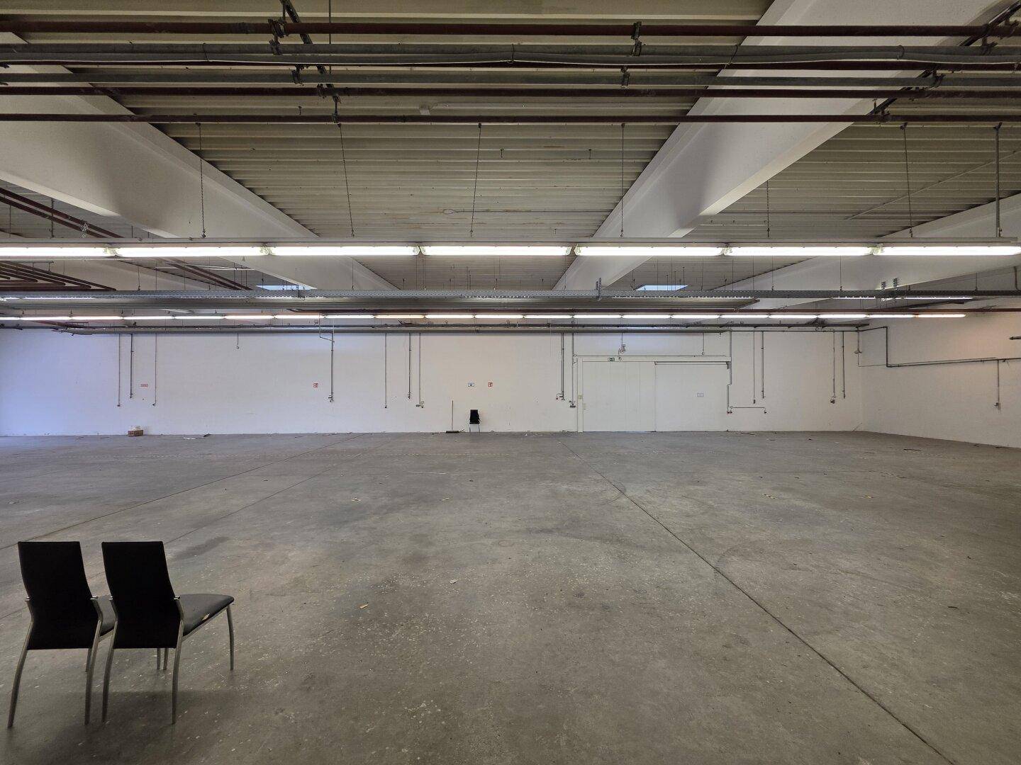 Geräumige, leere Lagerhalle mit Betonboden und minimalistischer Einrichtung, bereit für neue Mieter.