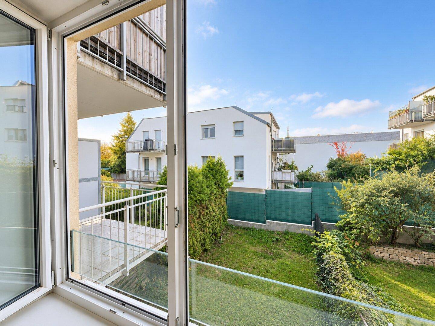 Blick von einem Balkon auf die umliegenden Gebäude und die grüne Umgebung.