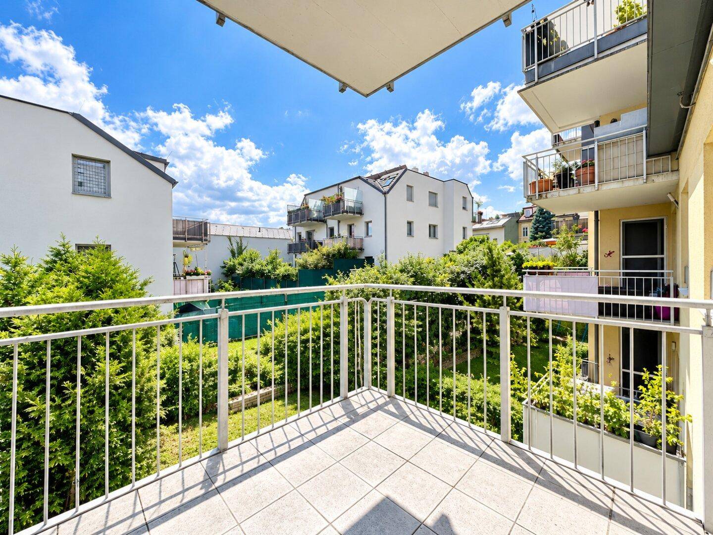 Geräumiger Balkon mit Fliesenboden und weitem Blick auf die umliegenden Wohngebäude und Grünflächen.