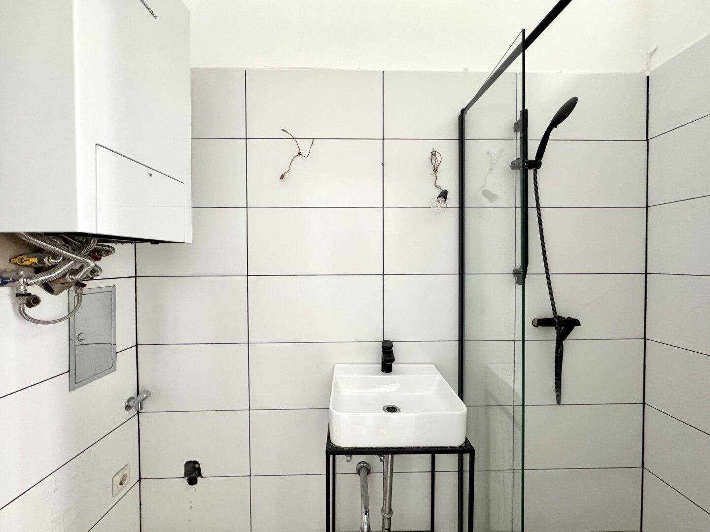 Modernisiertes Badezimmer mit Duschkabine, Waschbecken und Wandheizung.