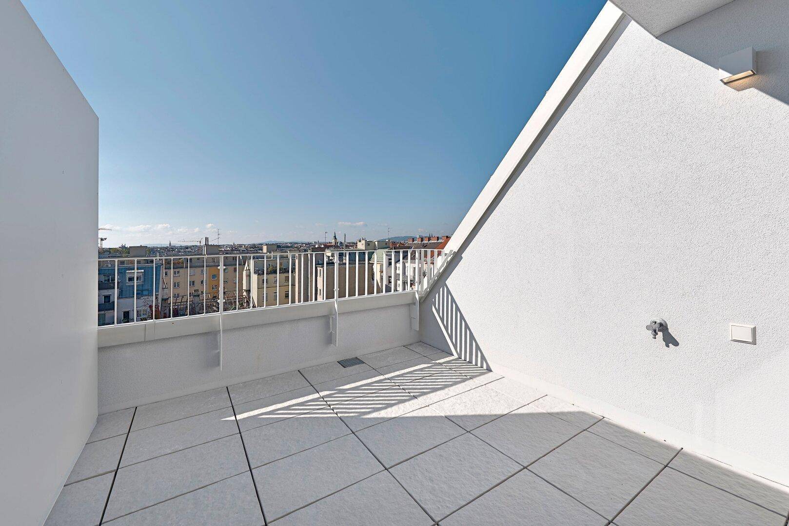 Sonniger Balkon mit Fliesenboden und weitem Blick über die Stadtlandschaft.