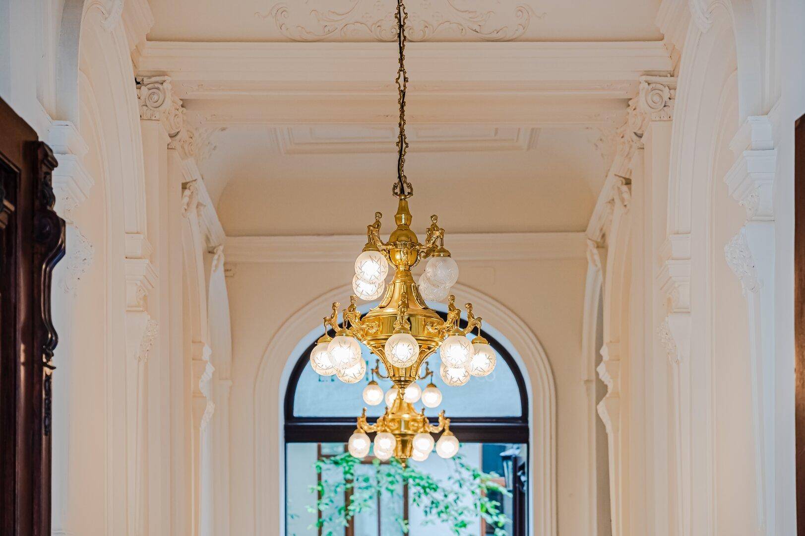 Eleganter Flur mit prunkvollem Kronleuchter und hohen Decken in einem Altbau.