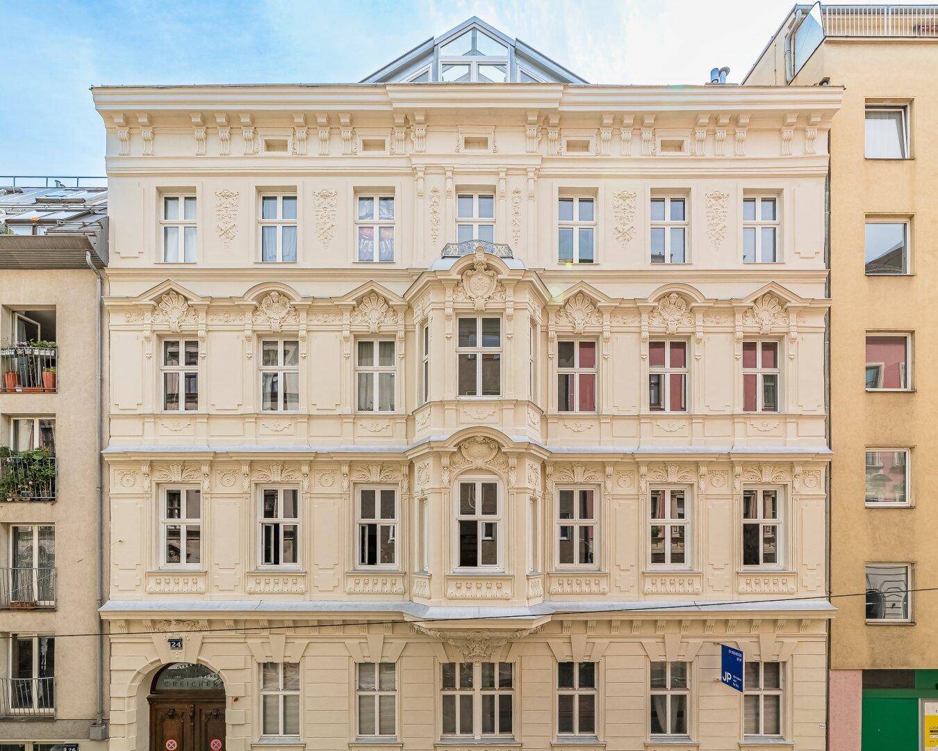 Prachtvolle Altbaufassade mit reich verzierten Details und großen Fenstern.
