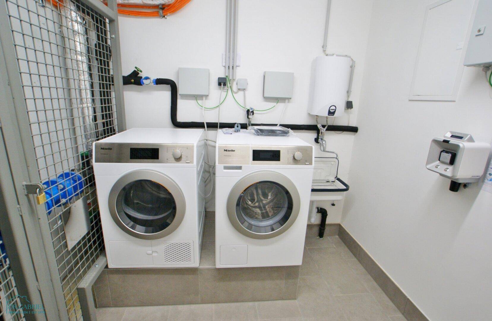 Gemeinschaftlicher Waschraum mit Waschmaschine und Trockner der Marke Miele.