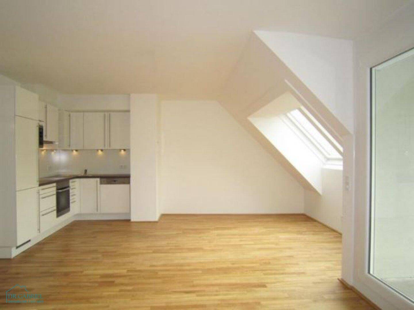 Moderne Einbauküche mit weißen Schränken und Holzboden in einem offenen Wohnbereich.