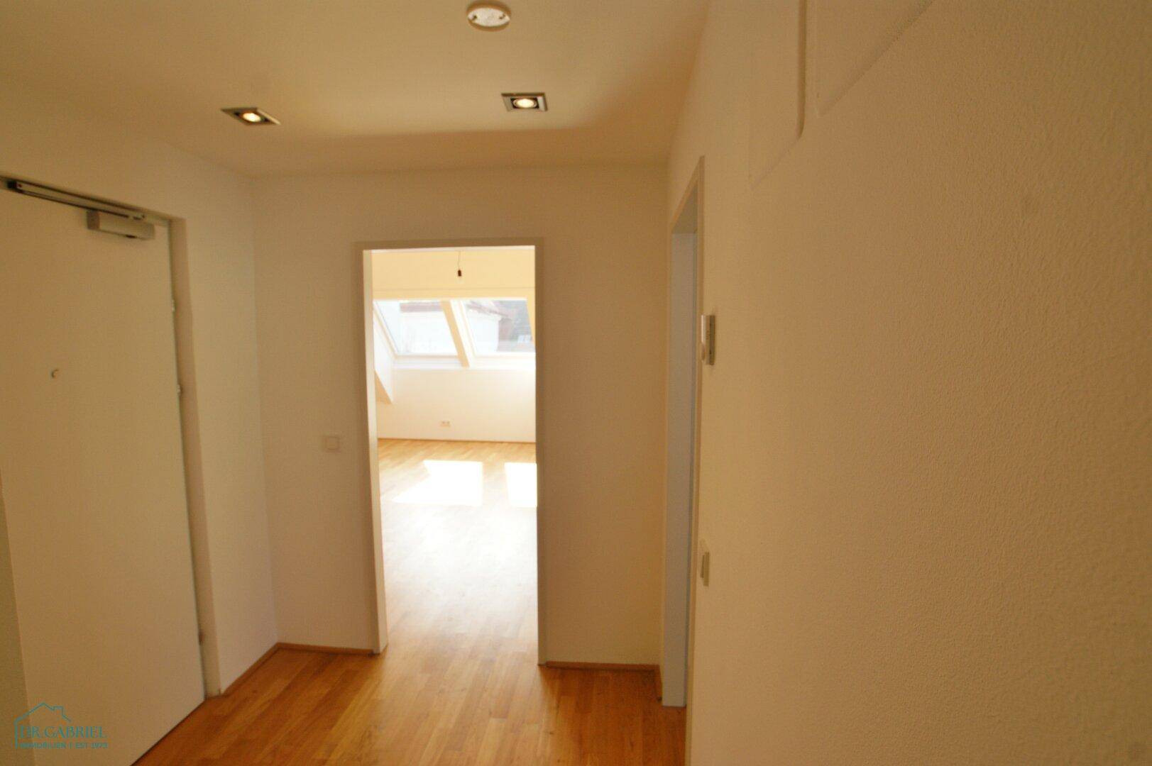 Heller Flur mit Holzboden und Zugang zu weiteren Räumen, gut beleuchtet.