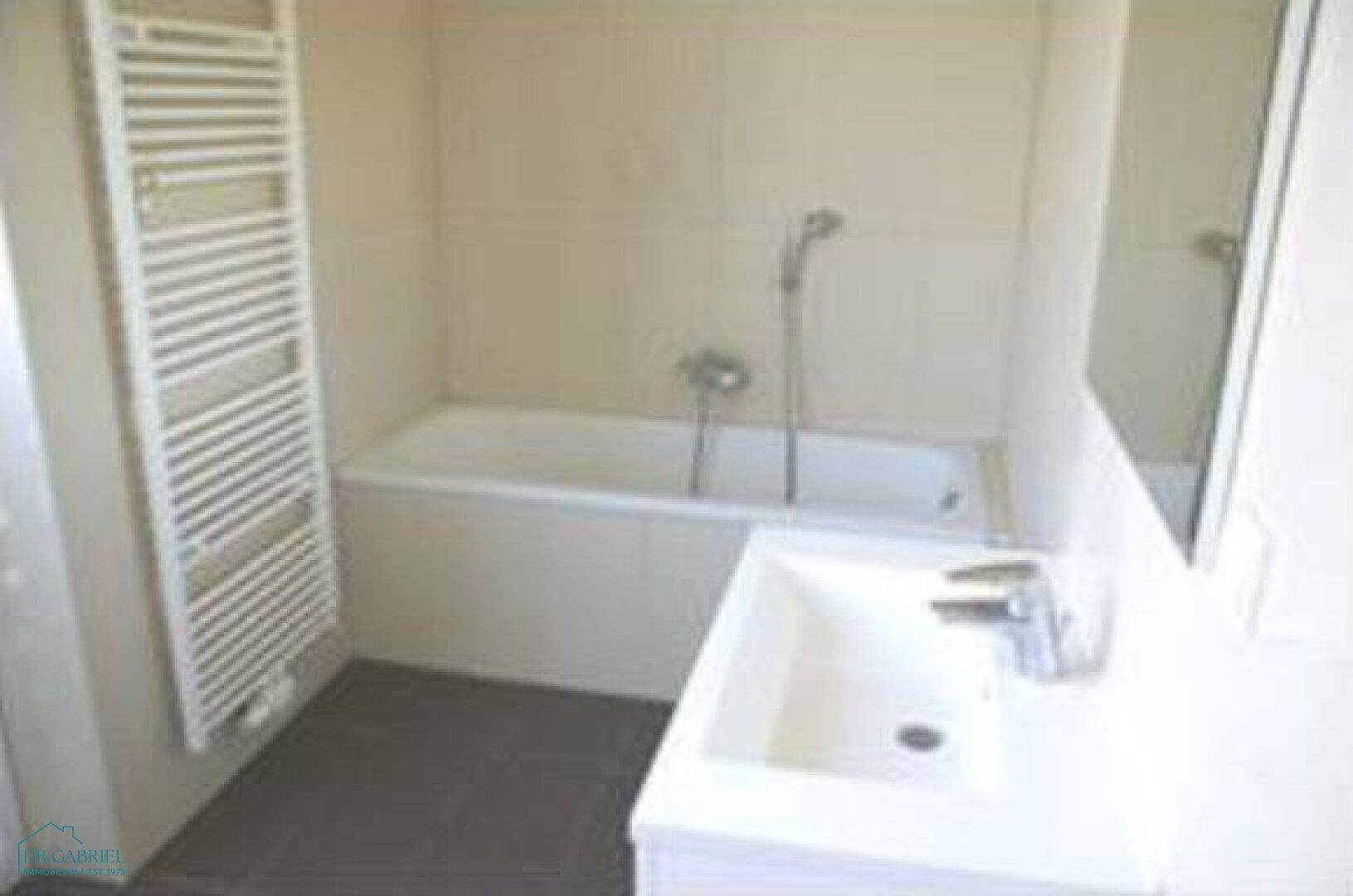 Modernes Badezimmer mit Badewanne, Waschbecken und beheiztem Handtuchhalter.