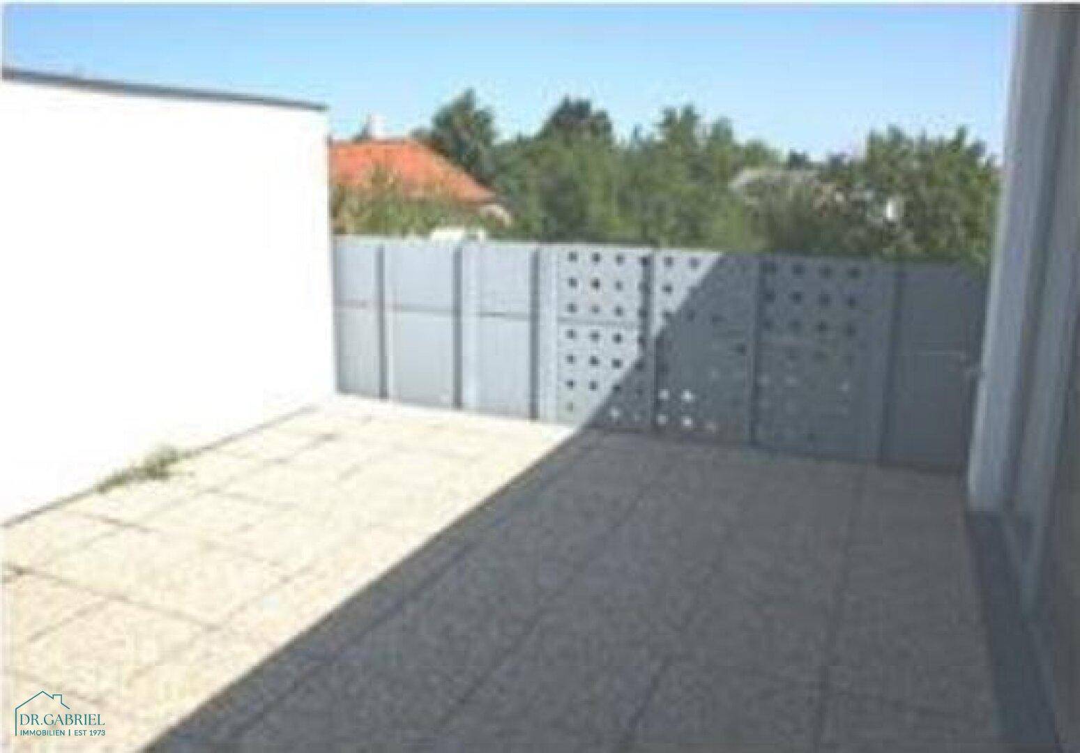 Geräumige, gepflasterte Terrasse mit Sichtschutz und Blick ins Grüne.
