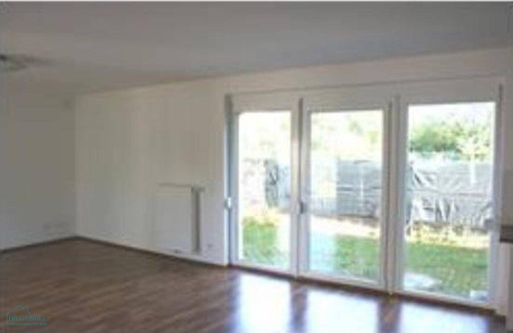 Lichtdurchfluteter Wohnbereich mit Parkettboden und direktem Zugang zum Garten.