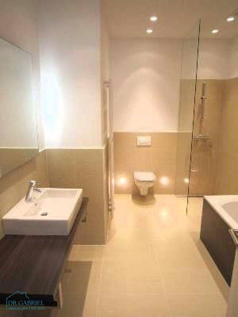 Elegantes Badezimmer mit Dusche, wandhängendem WC, Einzelwaschbecken und modernen Fliesen.