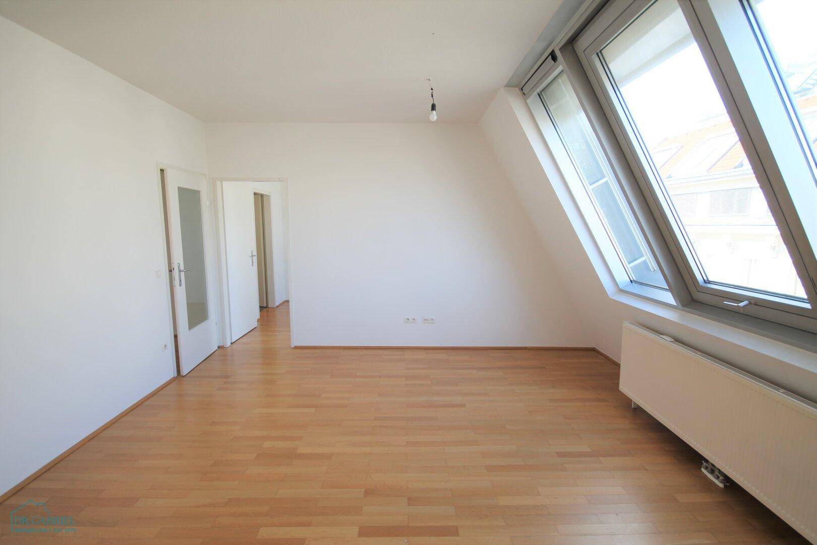 Heller Wohnbereich mit Holzparkett und schrägen Dachfenstern, die viel Licht hereinlassen.