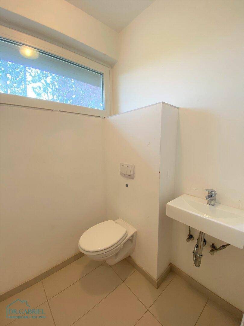 Kleines Gäste-WC mit Toilette, Waschbecken und Fenster, funktional und hell.