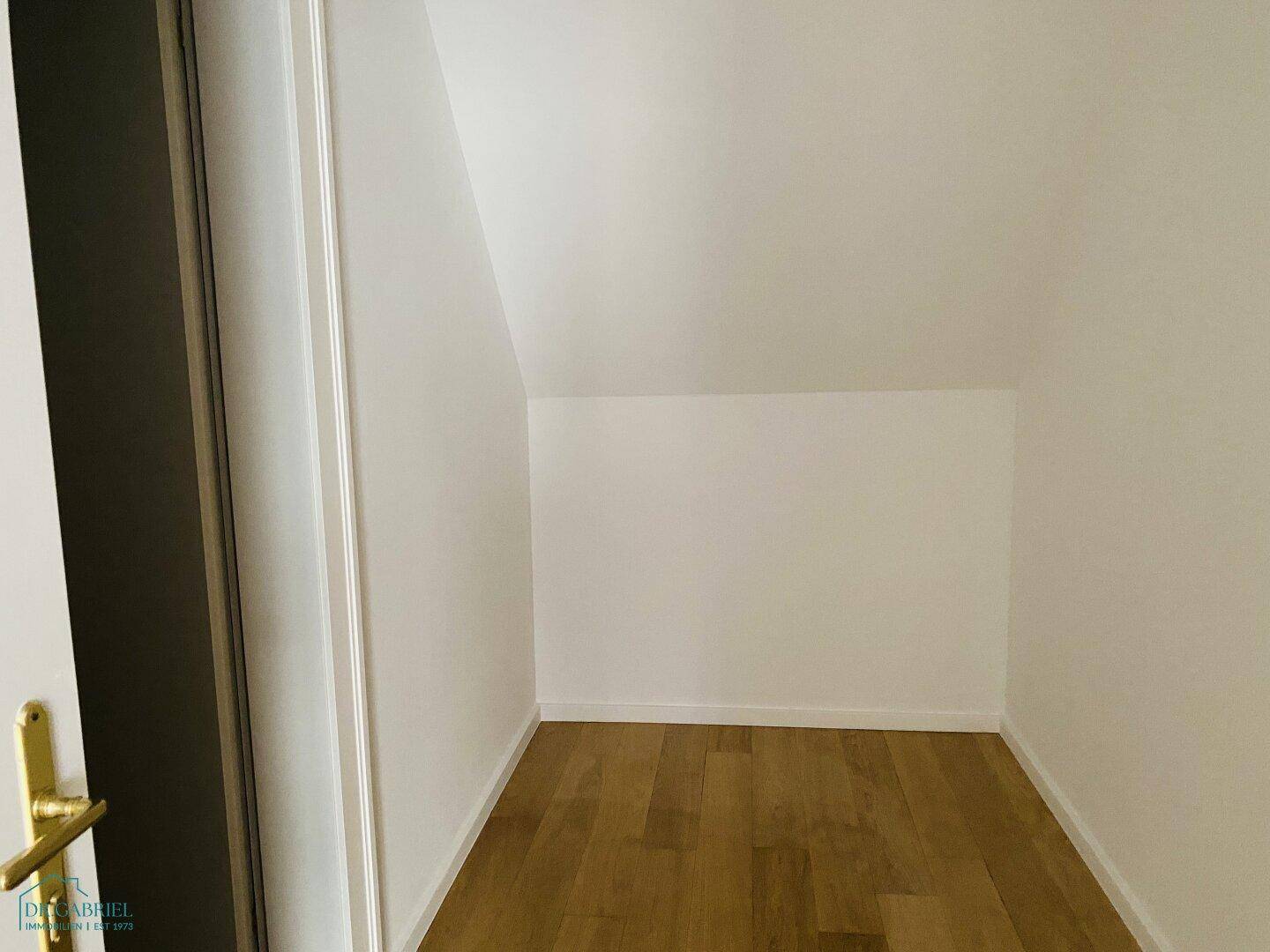 Praktischer Abstellraum mit Holzparkettboden und schrägen Wänden, gut nutzbar für Lagerzwecke.