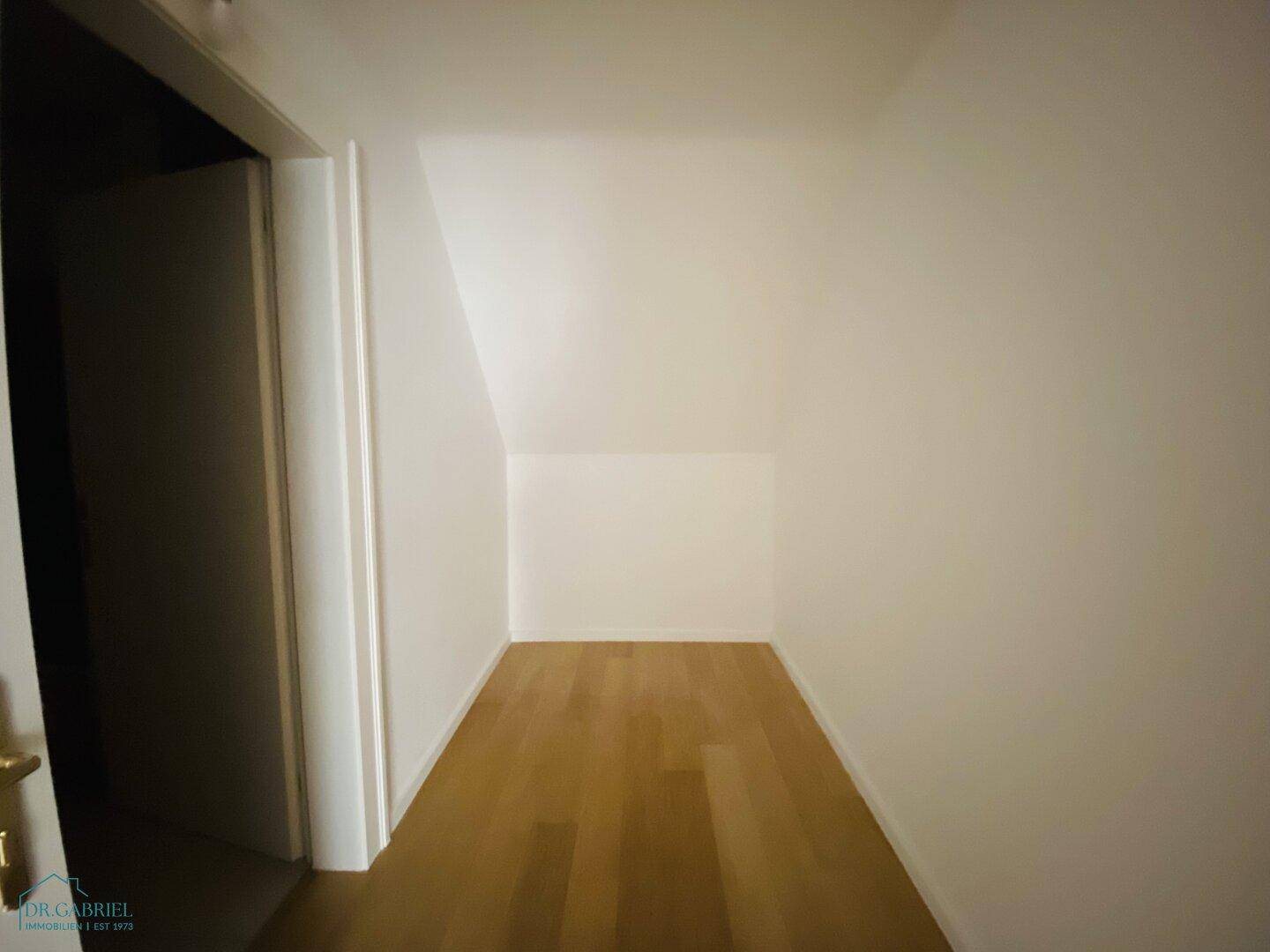 Kleiner Abstellraum mit Holzparkettboden und schrägen Wänden, ideal für zusätzlichen Stauraum.