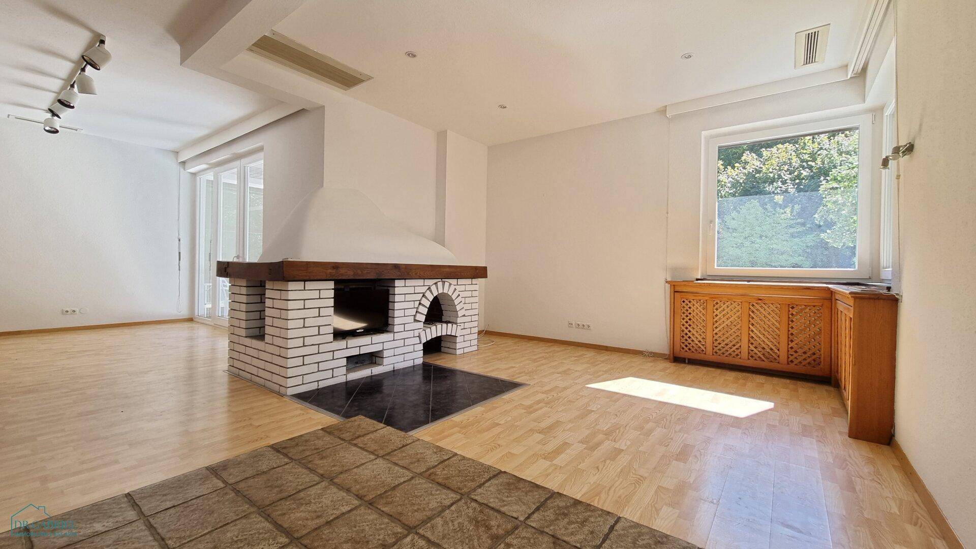 Wohnzimmer mit traditionellem Kamin aus weißen Ziegeln und hellem Holzboden, gut beleuchtet.