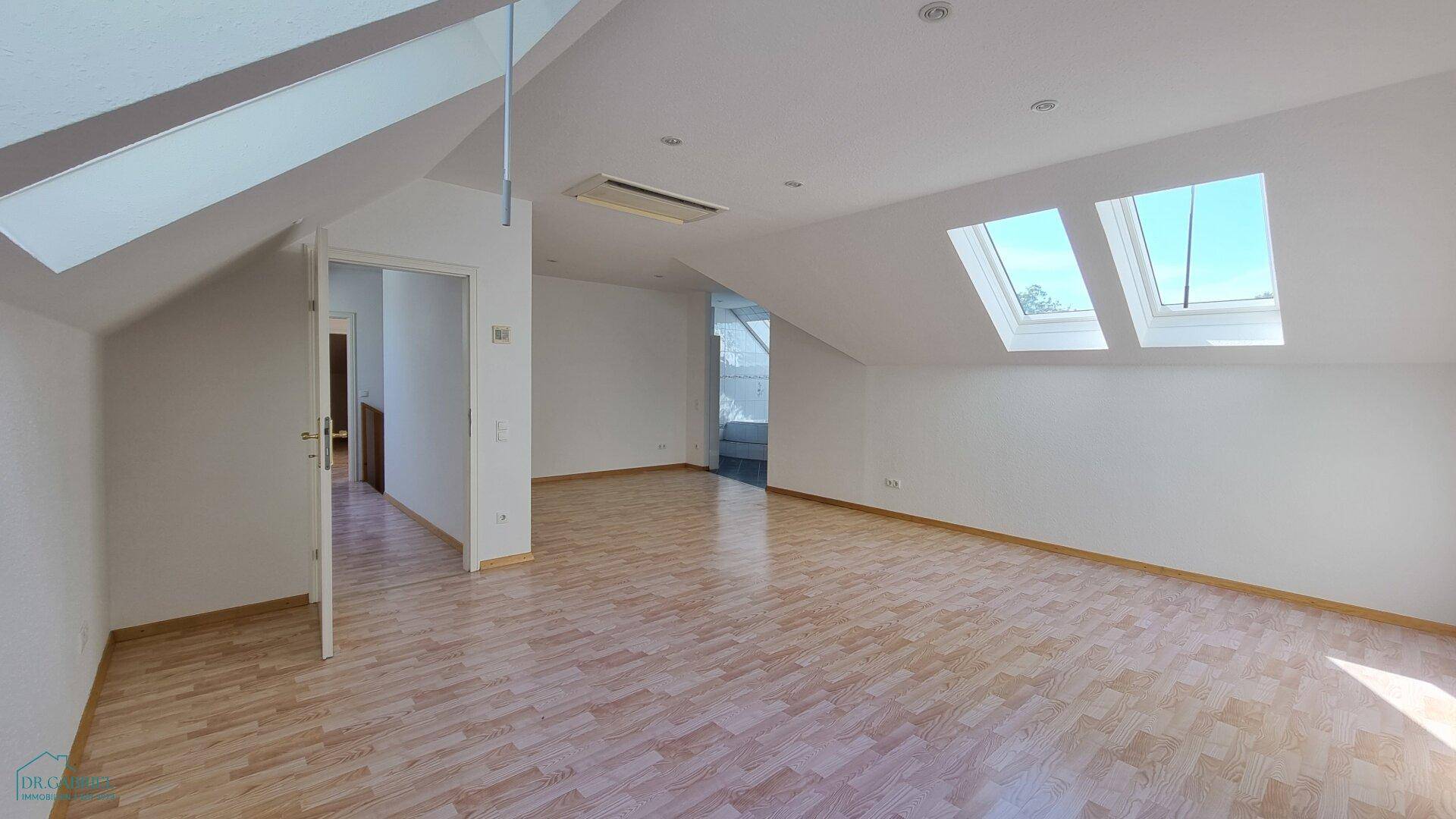 Heller und leerer Dachbodenraum mit Laminatboden und zwei großen Dachfenstern, bereit zur individuellen Gestaltung.