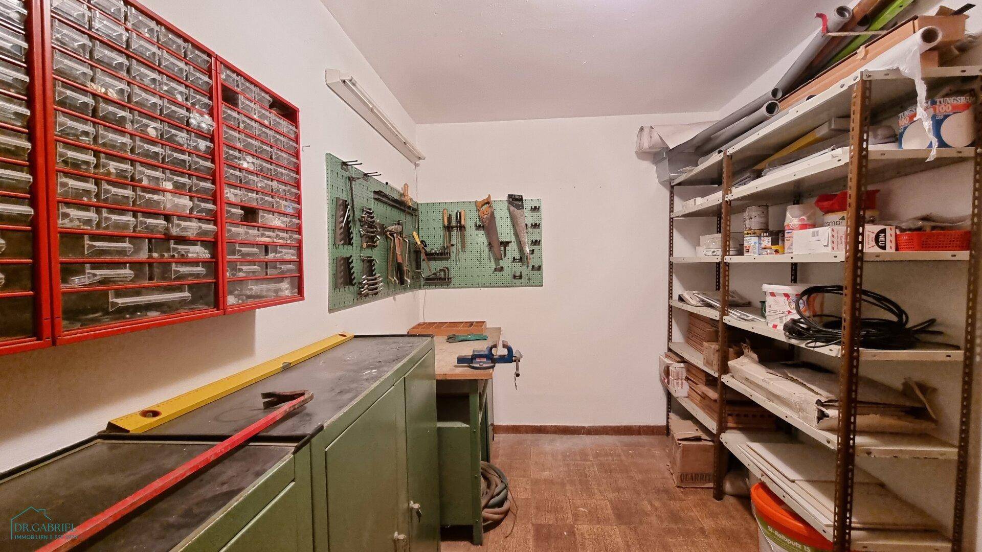 Gut ausgestatteter Werkstattraum mit Regalen, Werkzeugwand und Lagerschränken für verschiedene Materialien.