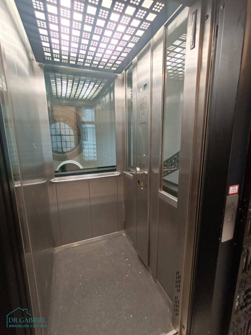Moderner Aufzug mit Edelstahlverkleidung und Glasfenster im Inneren des Gebäudes.