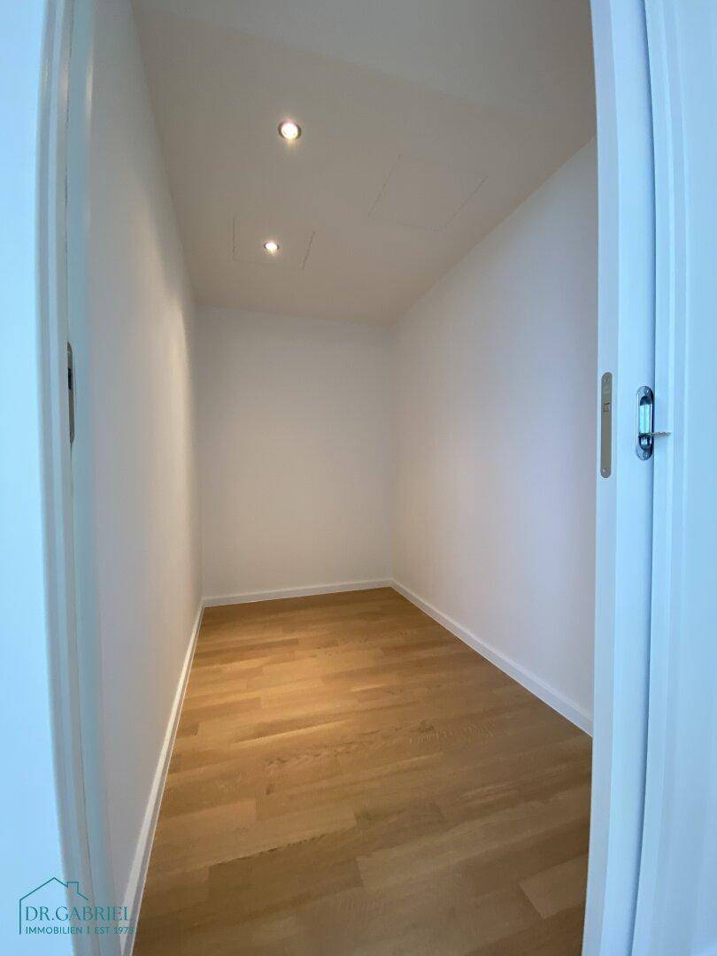 Praktischer Abstellraum mit Holzboden und integrierter Beleuchtung, ideal für zusätzlichen Stauraum.