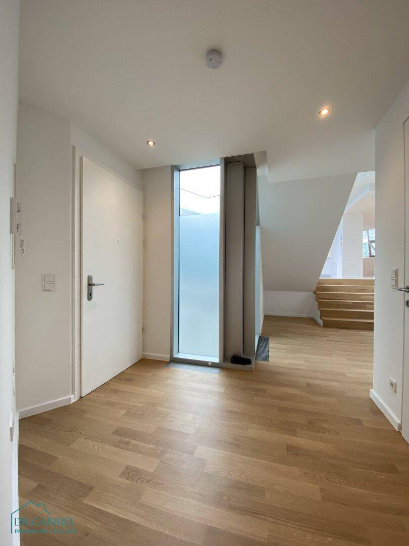 Heller Eingangsbereich mit Holzboden und moderner Tür, die zu den Wohnbereichen führt.
