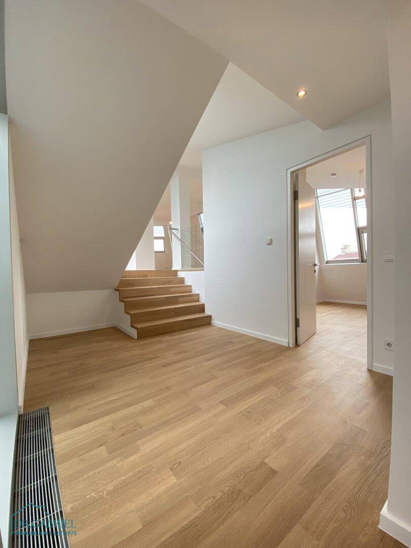 Geräumiger Eingangsbereich mit Holzboden und offener Treppe, die die verschiedenen Ebenen verbindet.