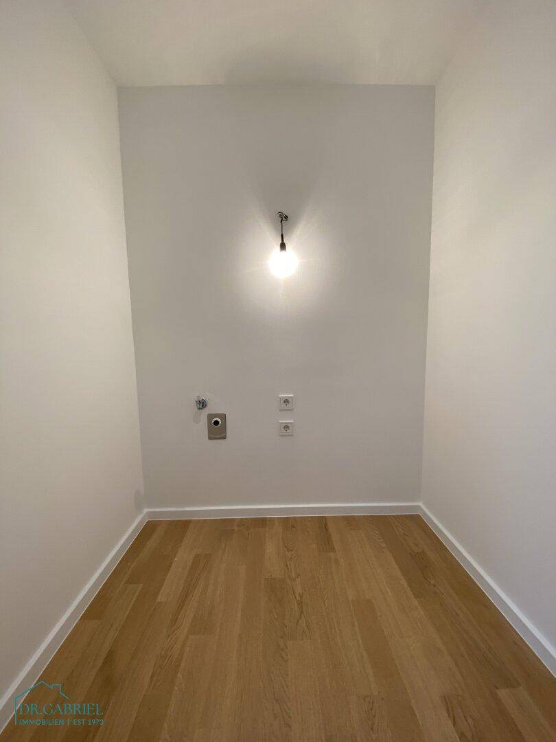 Kleiner Raum mit Holzfußboden und Anschlüssen, ideal als Hauswirtschaftsraum nutzbar.