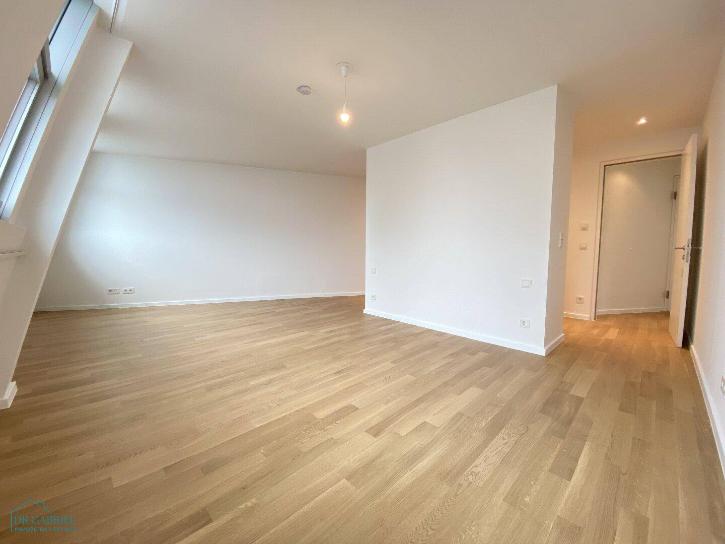 Geräumiges Schlafzimmer mit Holzboden und schrägen Fenstern, das viel Potenzial für individuelle Einrichtung bietet.
