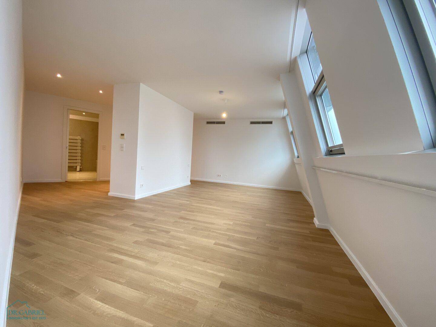 Heller Flurbereich mit Holzboden, der zu weiteren Räumen und einem modernen Badezimmer führt.