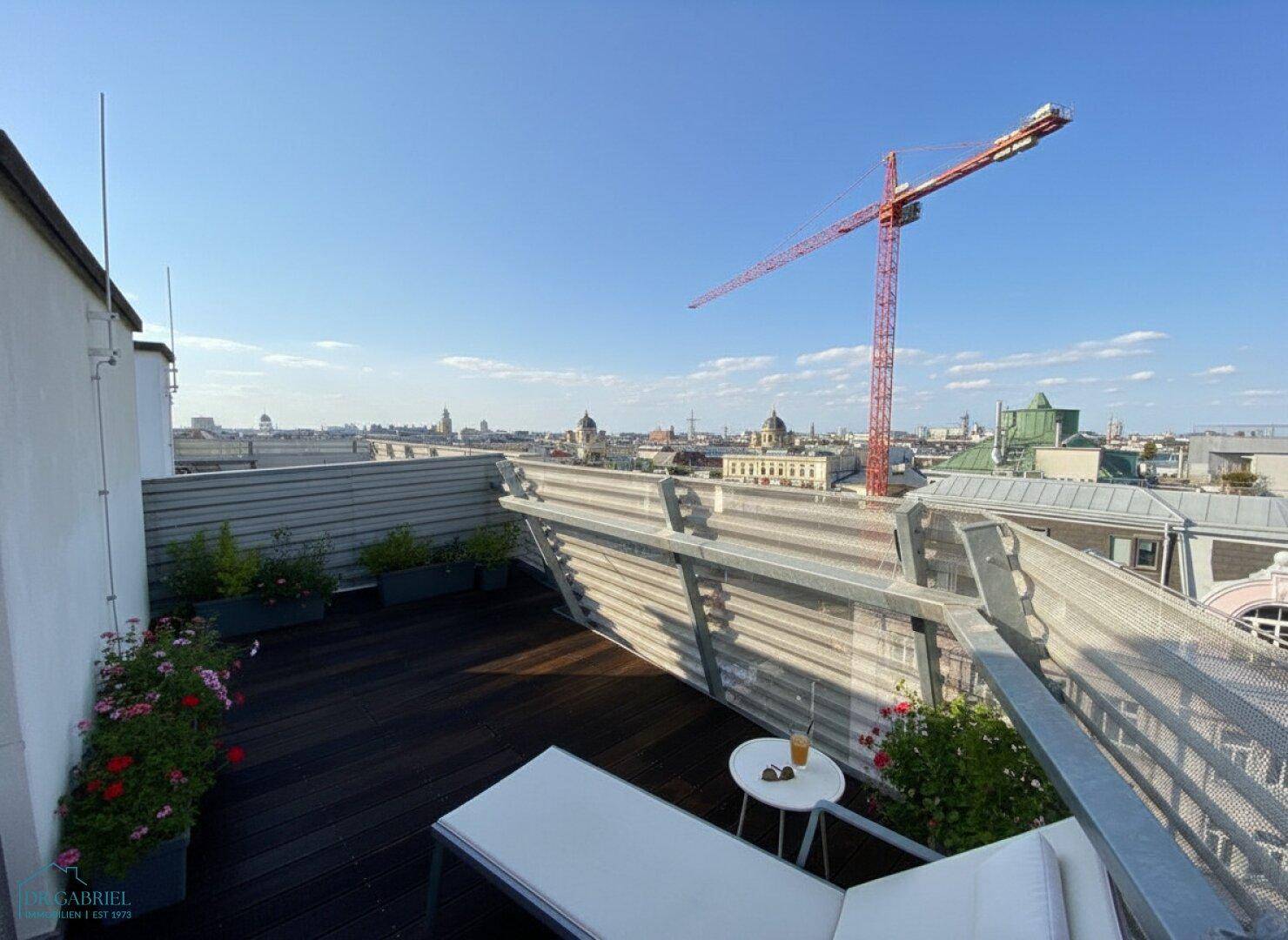 Weitläufige Dachterrasse mit Liegestuhl und Panoramablick über die Stadt, ideal zum Entspannen.