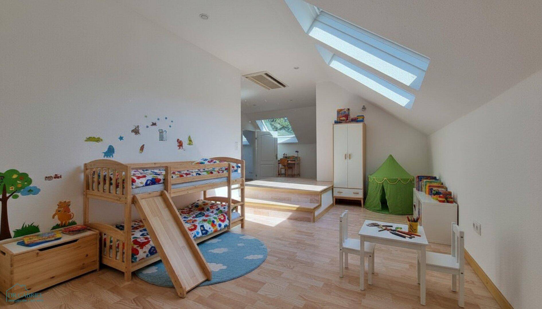 Helles Kinderzimmer im Dachgeschoss mit Etagenbett, Rutsche und Spielbereich unter Dachfenstern.