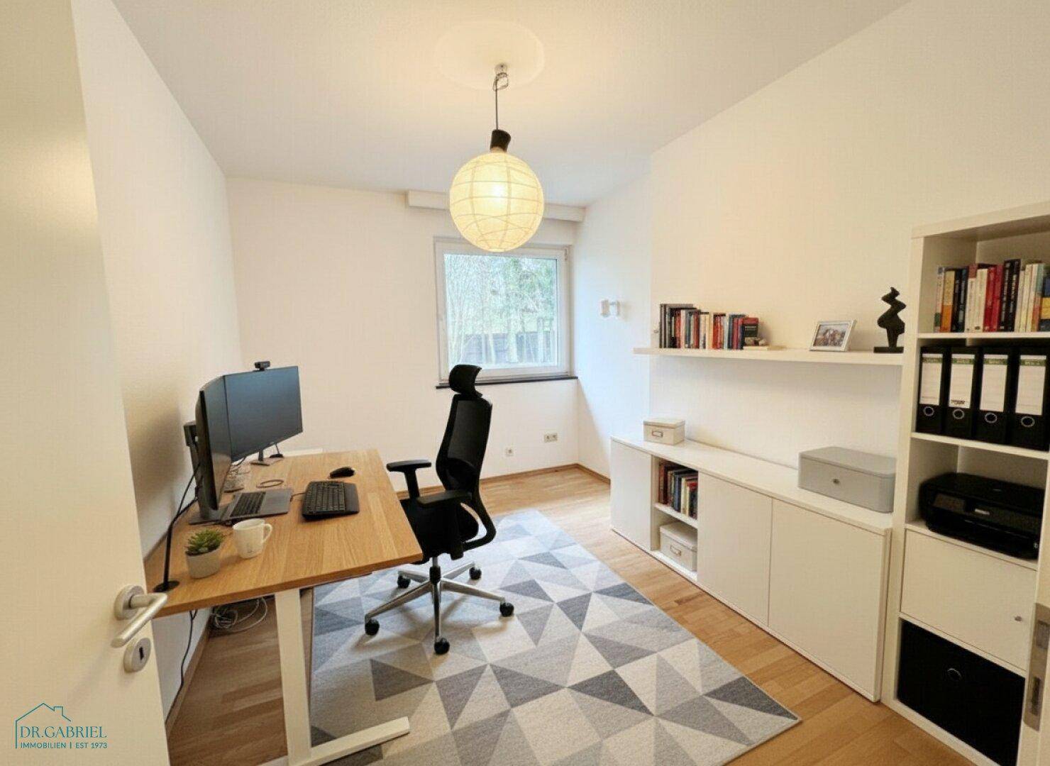 Helles Heimbüro mit Schreibtisch, Bürostuhl und Regalen, ideal für produktives Arbeiten.