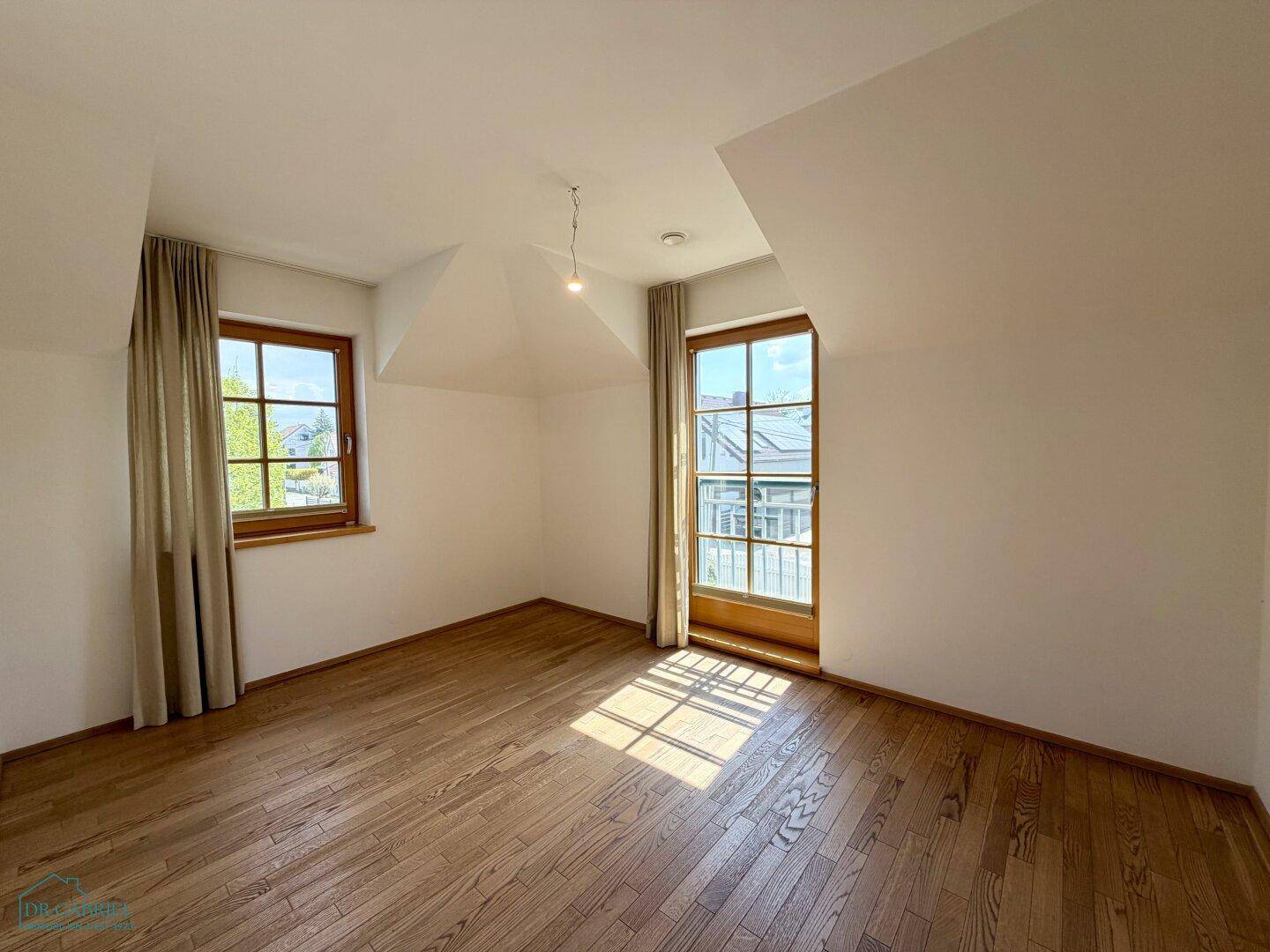 Helles Schlafzimmer im Dachgeschoss mit Holzboden, Dachschrägen und französischem Balkon.