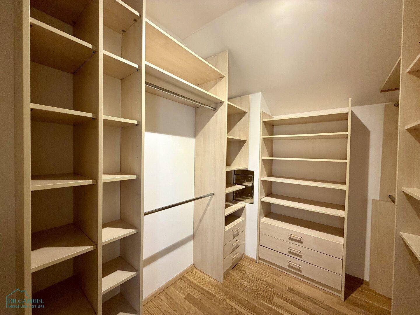 Geräumiger begehbarer Kleiderschrank mit vielen Regalen und Schubladen für optimale Organisation.